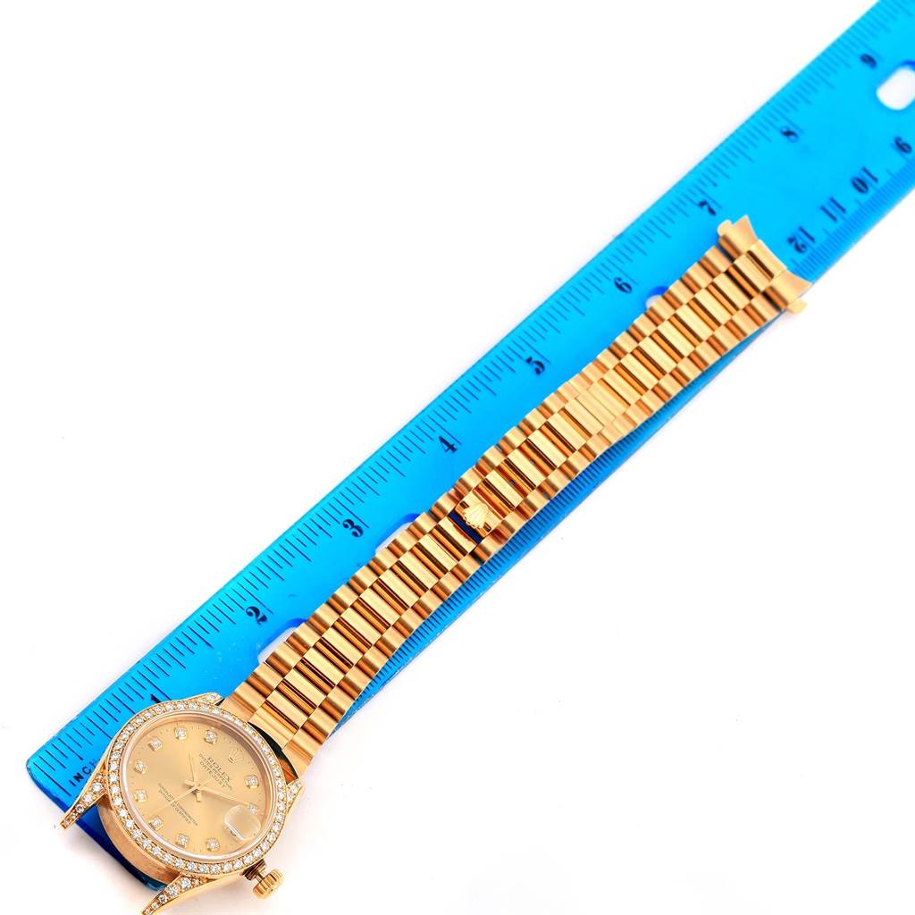 This image shows the Rolex President 68158 Women's Yellow Gold Champagne Dial 68158 Women's Yellow Gold Champagne Dial model watch laid flat with a blue ruler for scale, displaying the face, bezel, and full bracelet.