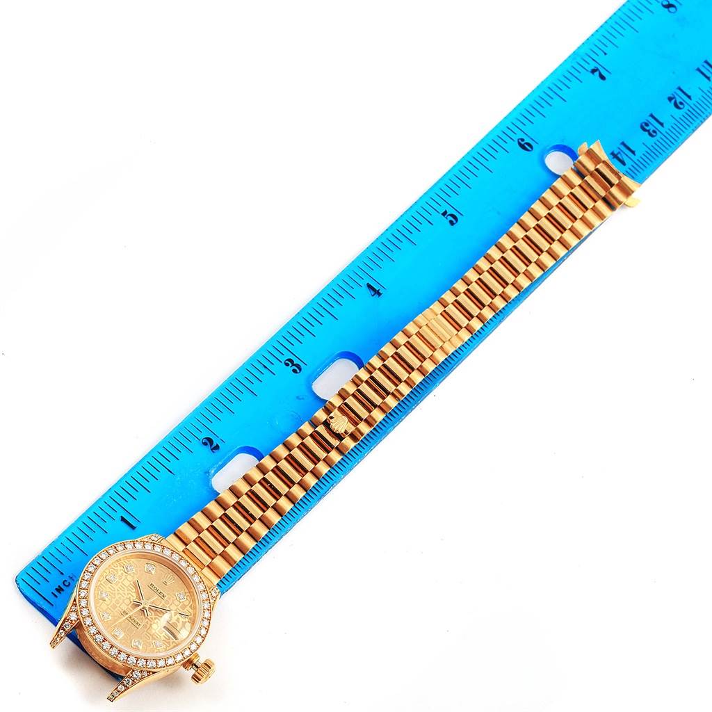 The Rolex President 69158 Women's Yellow Gold Champagne Dial 69158 Women's Yellow Gold Champagne Dial model watch is shown flat with a blue ruler measuring its bracelet and face.