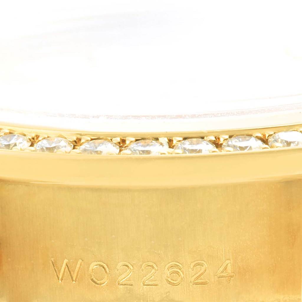 This close-up image of a Rolex President 69158 Women's Yellow Gold Champagne Dial 69158 Women's Yellow Gold Champagne Dial watch shows the serial number on the gold case and part of the diamond-set bezel.
