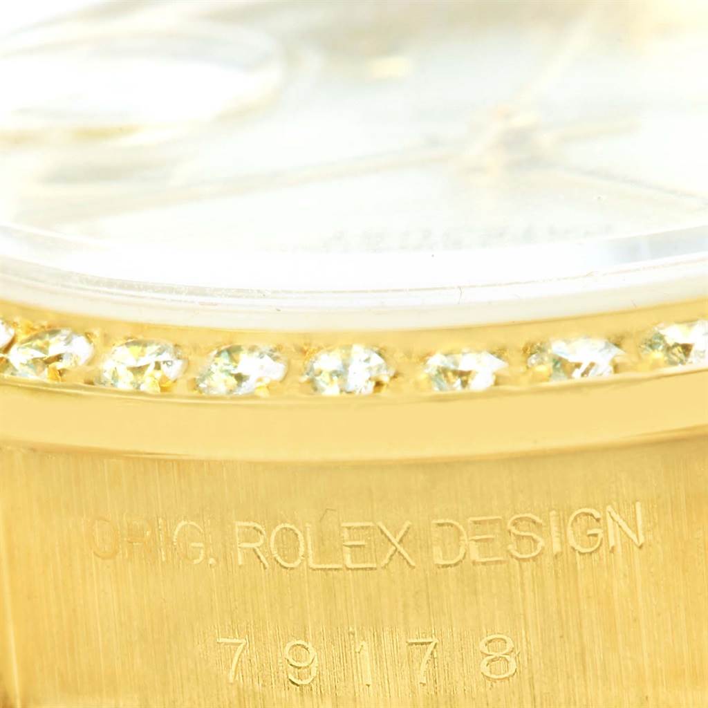 The image shows a close-up of the Rolex President 79178 Women's Yellow Gold Mother of Pearl Dial 79178 Women's Yellow Gold Mother of Pearl Dial model watch's gold bezel with diamond accents, and part of the watch's case with the engraving "ORIG. ROLEX DESIGN" and the model number "79178".