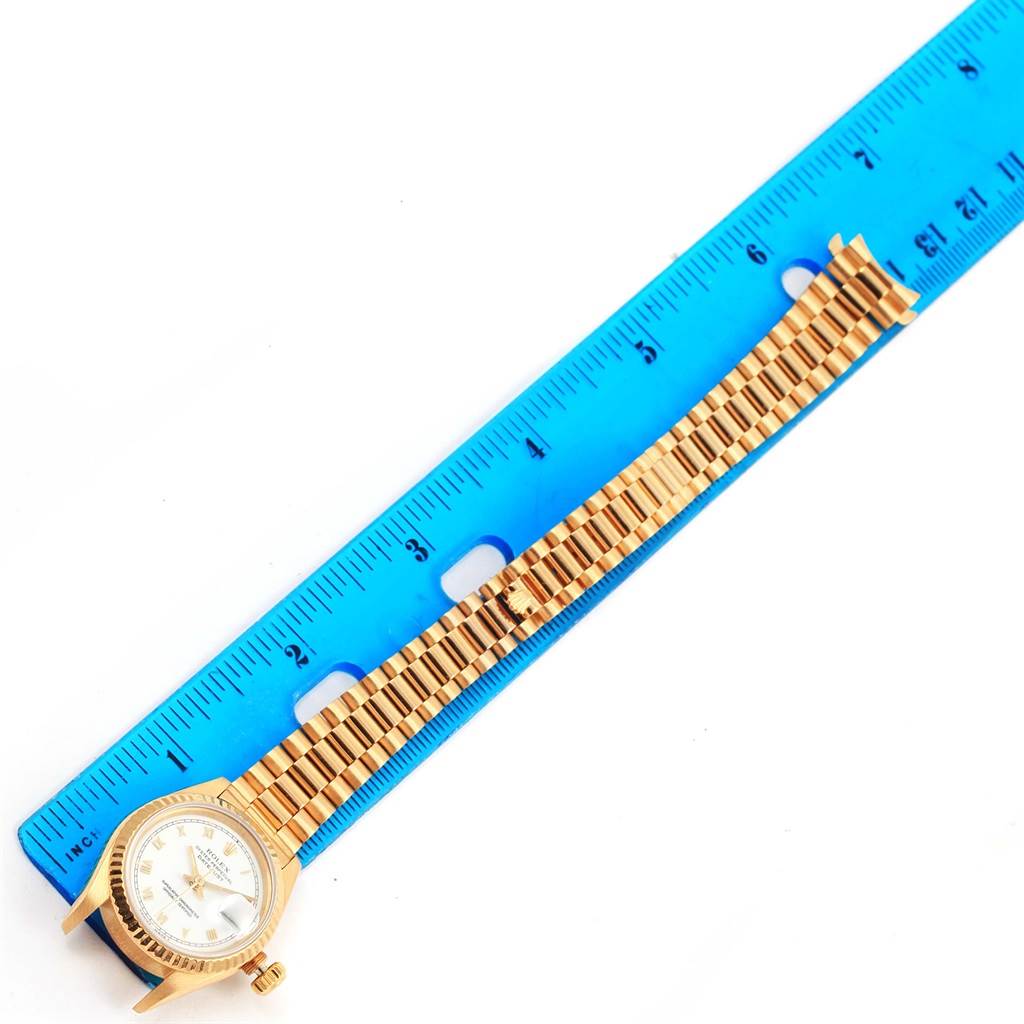 The Rolex President 69178 Women's Yellow Gold White Dial 69178 Women's Yellow Gold White Dial model watch is shown flat with the face and full gold bracelet visible alongside a blue ruler for scale.