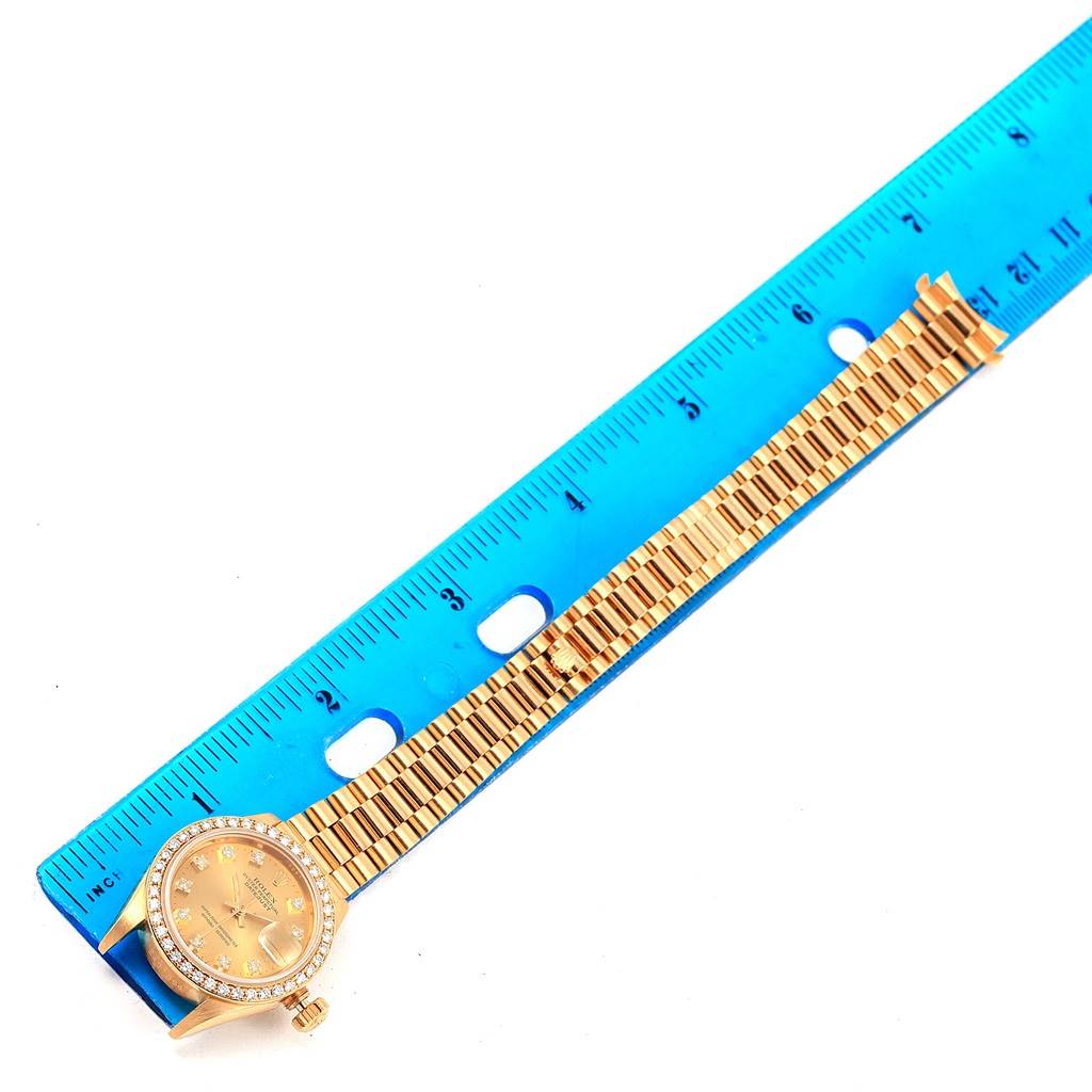 The image shows a Rolex President 69138 Women's Yellow Gold Champagne Dial 69138 Women's Yellow Gold Champagne Dial model watch laid flat next to a ruler, displaying the watch face and band.