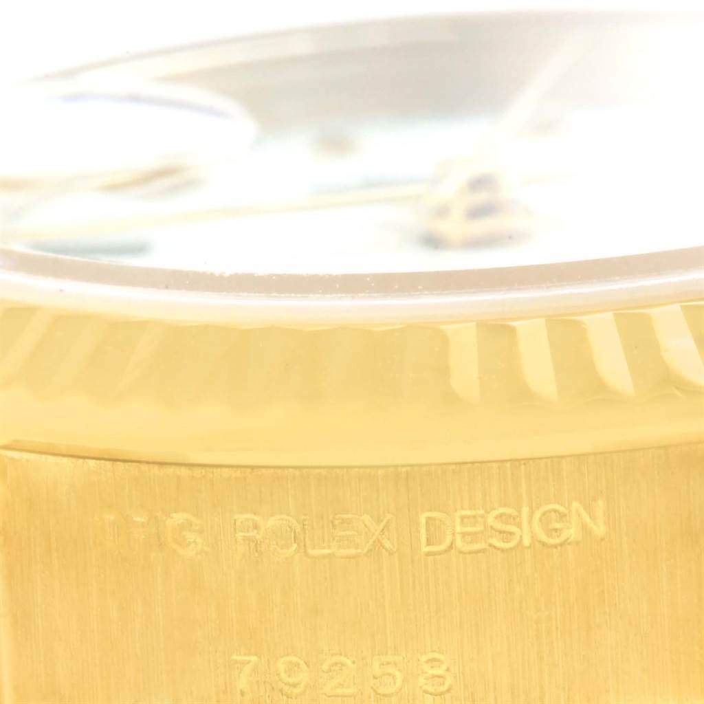 This close-up image of a Rolex President 79258 Women's Yellow Gold White Dial 79258 Women's Yellow Gold White Dial watch shows its gold case edge and the "ORIG ROLEX DESIGN" engraving.
