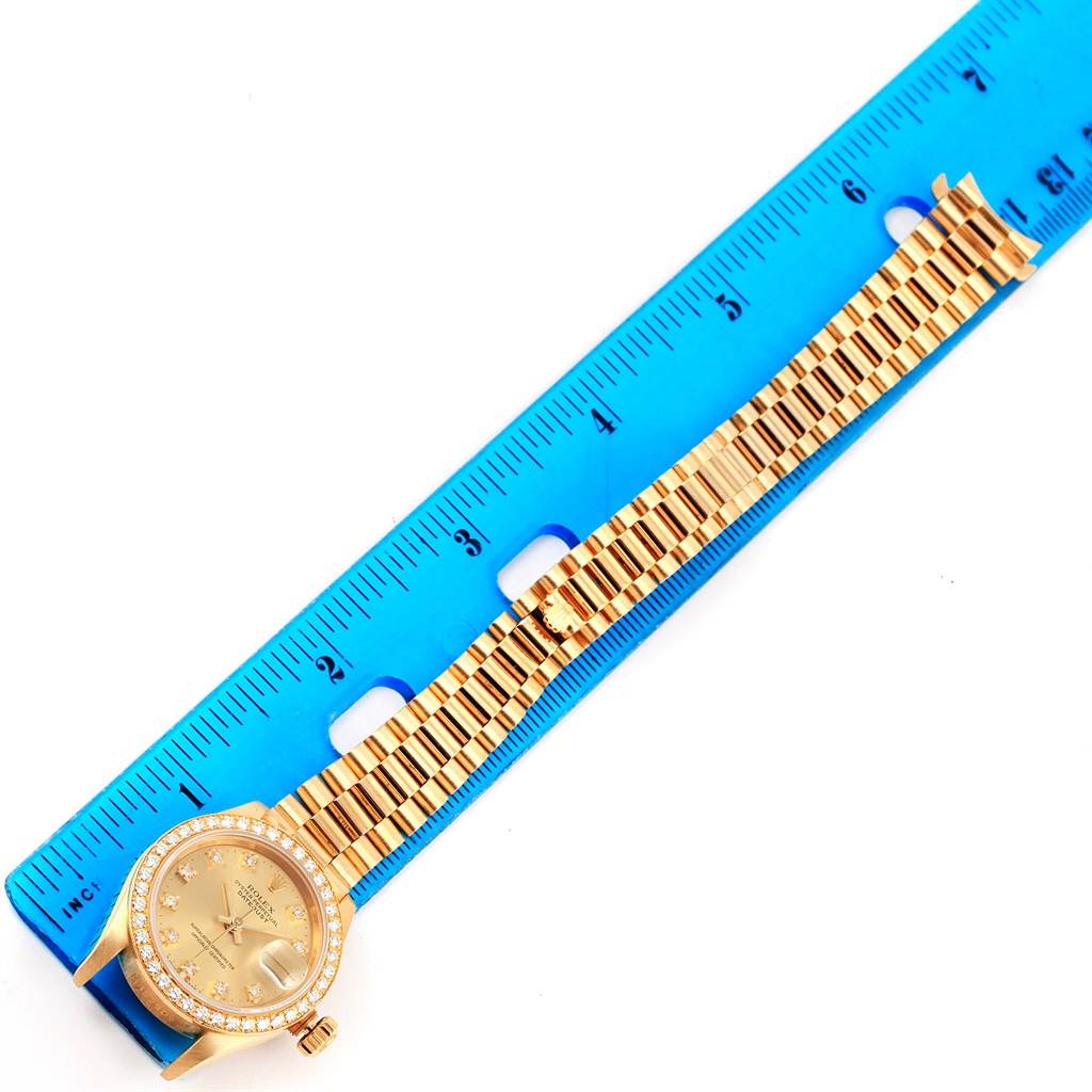 The Rolex President 69178 Women's Yellow Gold Champagne Dial 69178 Women's Yellow Gold Champagne Dial model watch is shown laid flat next to a blue ruler, displaying the face, bezel, and bracelet.