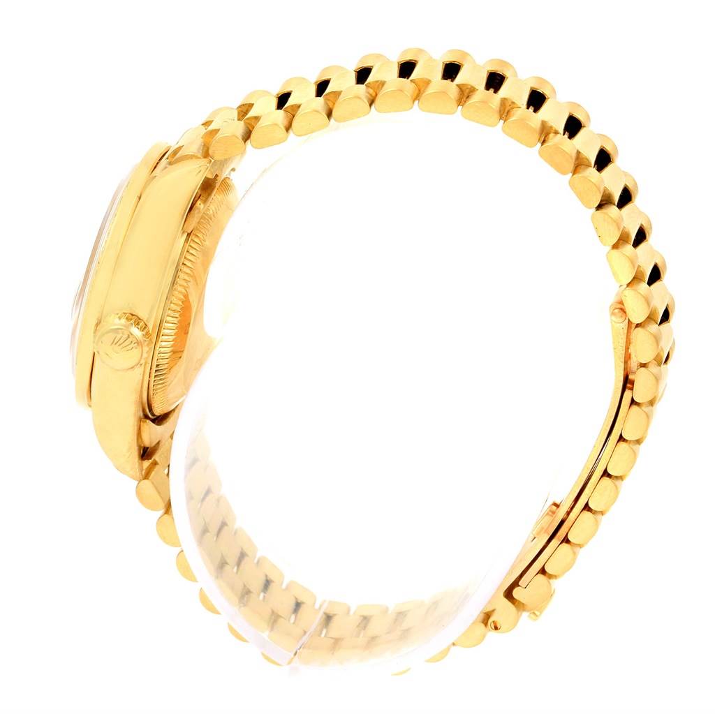 This side-angle view of the Rolex President 69178 Women's Yellow Gold Champagne Dial 69178 Women's Yellow Gold Champagne Dial model showcases the crown and part of the gold bracelet.