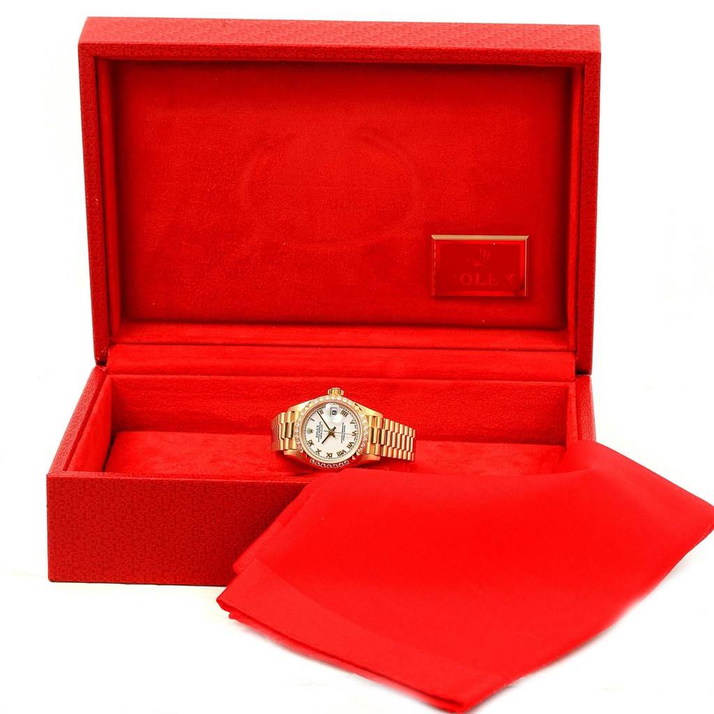 The Rolex President 79268 Women's Yellow Gold White Dial 79268 Women's Yellow Gold White Dial watch is displayed inside an open red box, with a polishing cloth beside it.