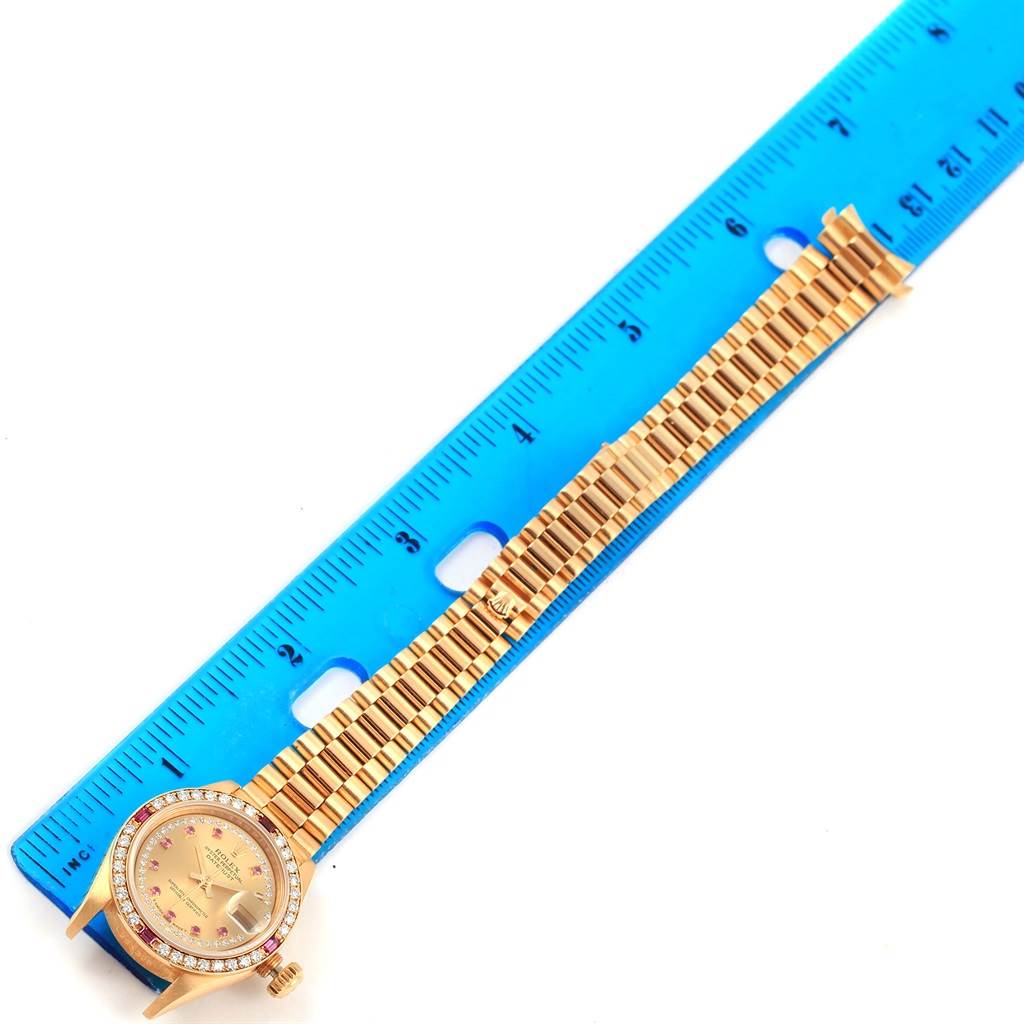 The Rolex President 69178 Women's Yellow Gold Champagne Dial 69178 Women's Yellow Gold Champagne Dial watch is shown from a top-down angle, with focus on its band and dial, alongside a ruler for scale.