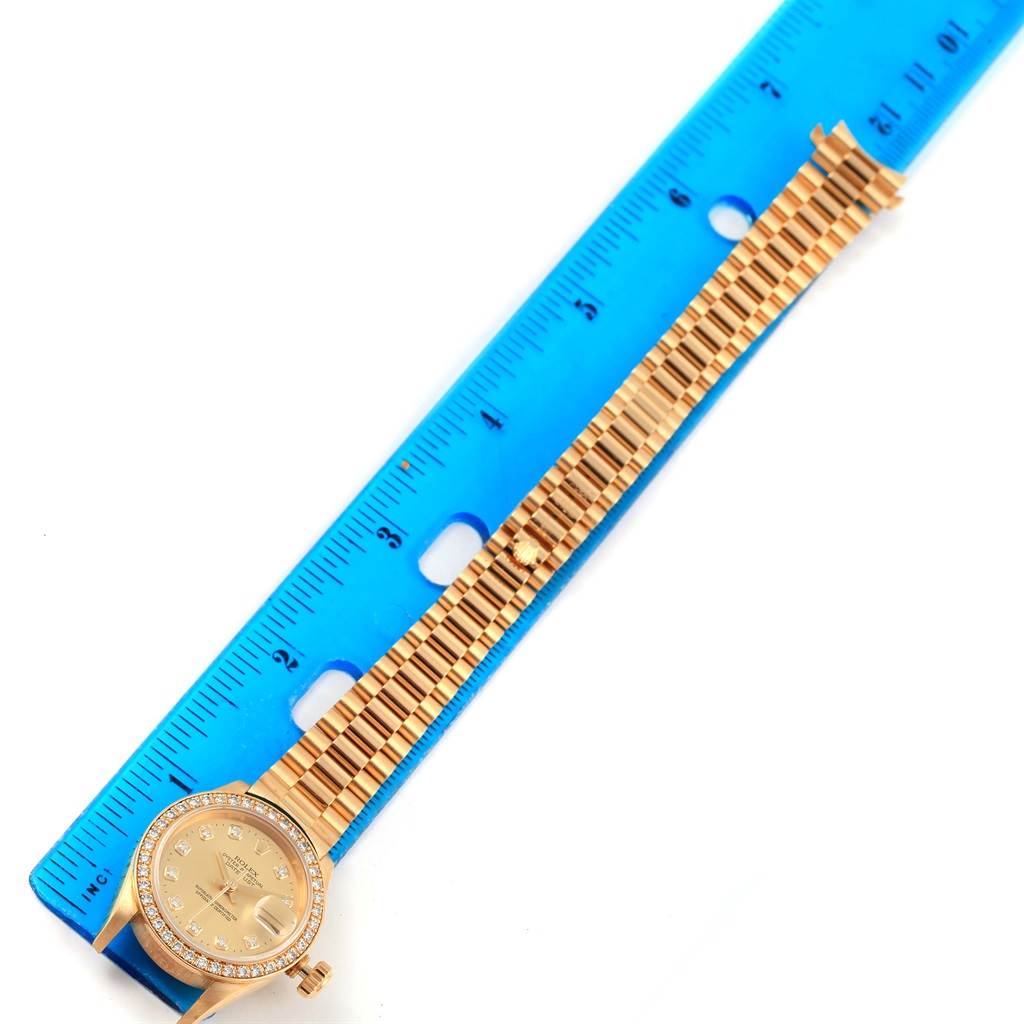 A Rolex President 69178 Women's Yellow Gold Champagne Dial 69178 Women's Yellow Gold Champagne Dial model watch is shown from a top-down angle, displayed alongside a blue ruler for scale.