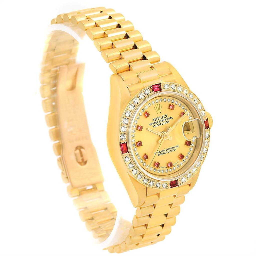 The image shows a side view of a Rolex President 69178 Women's Yellow Gold Champagne Dial 69178 Women's Yellow Gold Champagne Dial model watch, highlighting the gold band, bezel, and face with diamond and ruby detailing.
