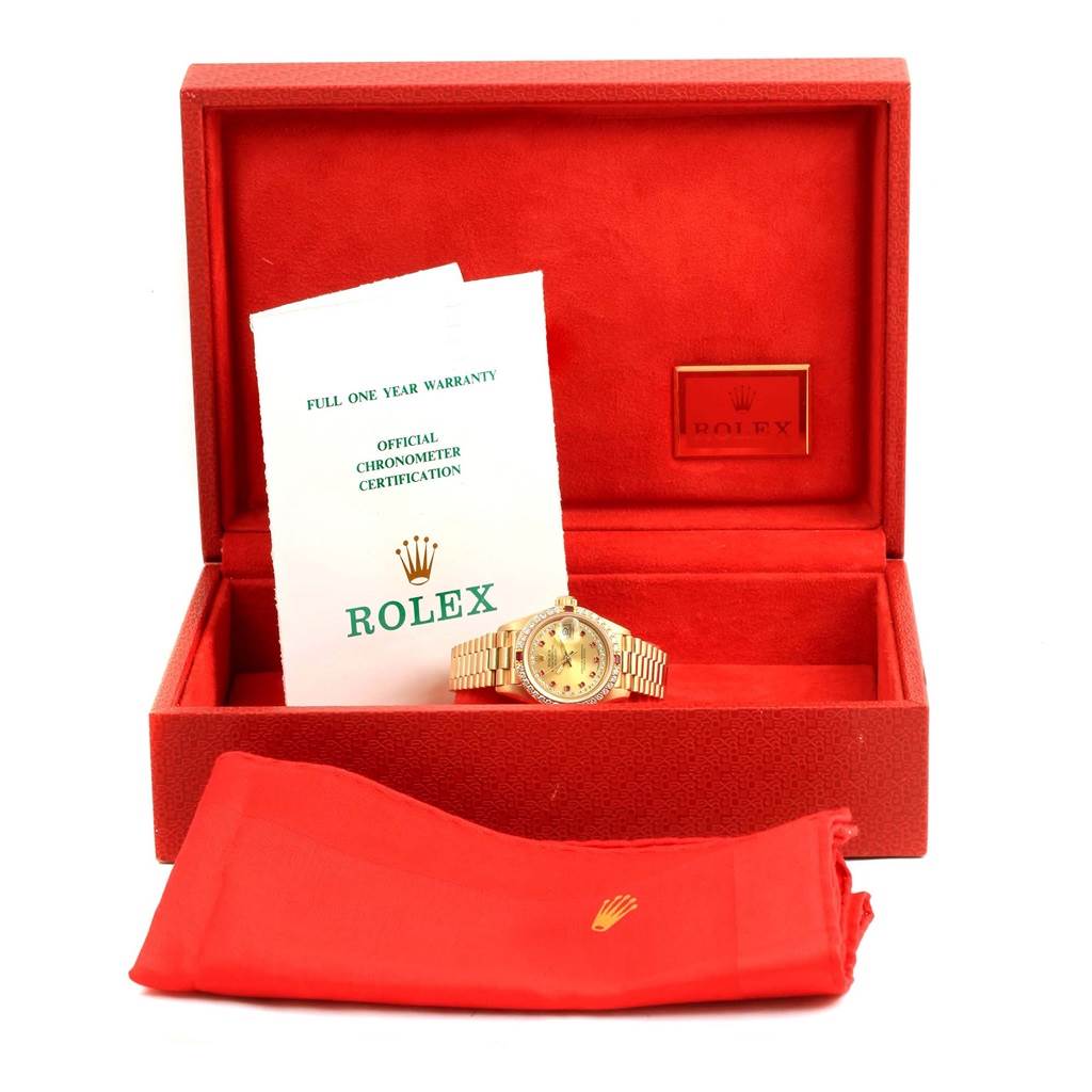 The Rolex President 69178 Women's Yellow Gold Champagne Dial 69178 Women's Yellow Gold Champagne Dial watch is shown inside its open red box, along with its warranty card and a red cloth.