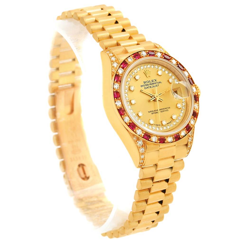 The Rolex President 69198 Women's Yellow Gold Champagne Dial 69198 Women's Yellow Gold Champagne Dial model watch is shown at a three-quarter angle, highlighting the gold bracelet, diamond and ruby bezel, and face.