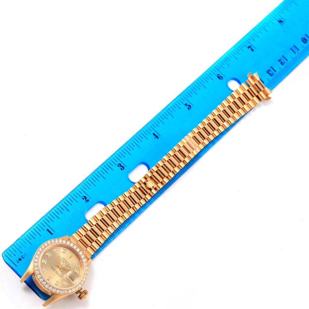 The image shows a President model Rolex watch laid flat with a blue ruler alongside it for measurement.