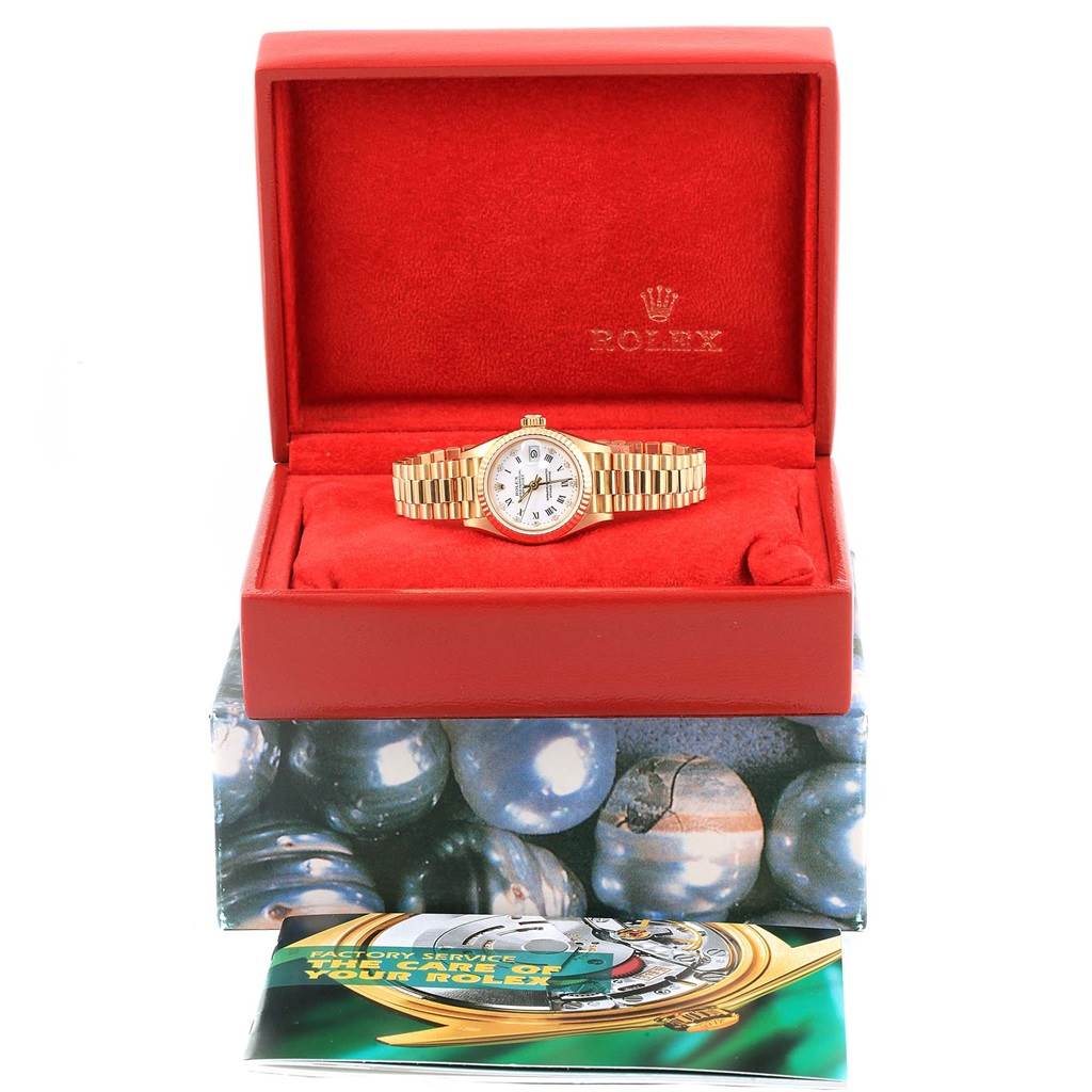 The image shows a Rolex President 69178 Women's Yellow Gold White Dial 69178 Women's Yellow Gold White Dial watch in its red case, displayed frontally, along with its accompanying booklet.