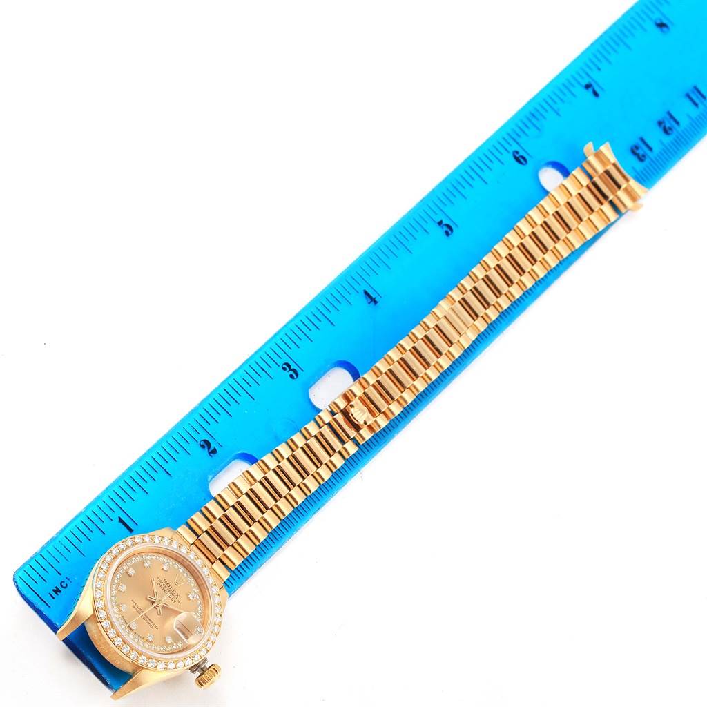 The image shows a Rolex President 69178 Women's Yellow Gold Champagne Dial 69178 Women's Yellow Gold Champagne Dial model watch laid flat next to a blue ruler for measurement.