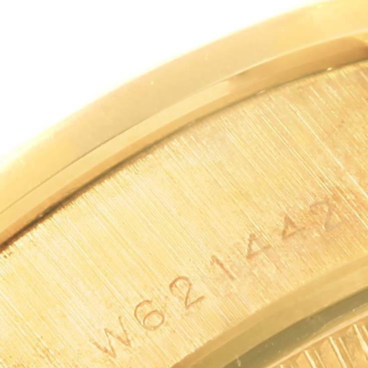 This close-up angle of a Rolex President 69138 Women's Yellow Gold White Dial 69138 Women's Yellow Gold White Dial watch showcases part of its golden case and engraved serial number.