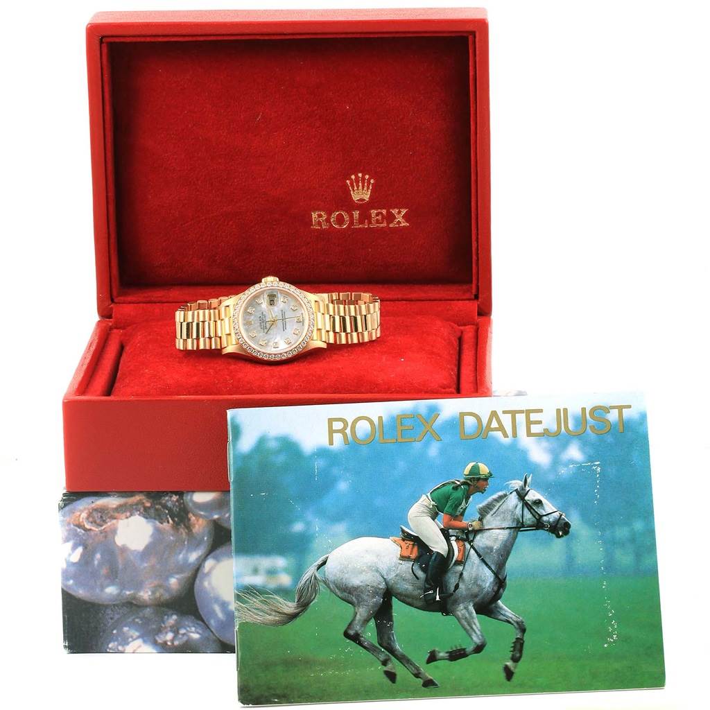 This image shows a Rolex President 79138 Women's Yellow Gold Mother of Pearl Dial 79138 Women's Yellow Gold Mother of Pearl Dial model watch inside its open red box with a Rolex Datejust booklet in front.