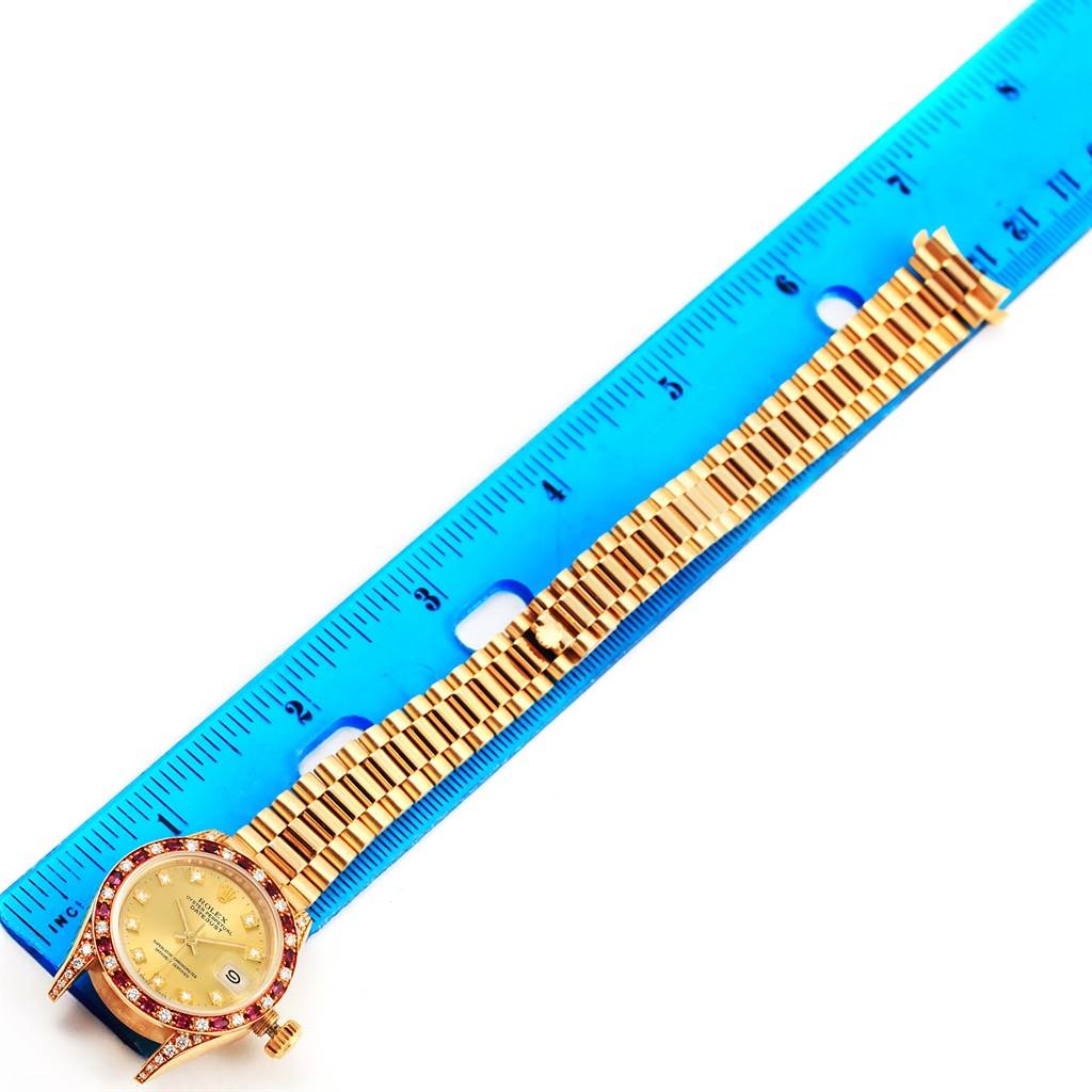 This image shows the President model Rolex watch placed alongside a blue ruler, highlighting its face and bracelet.