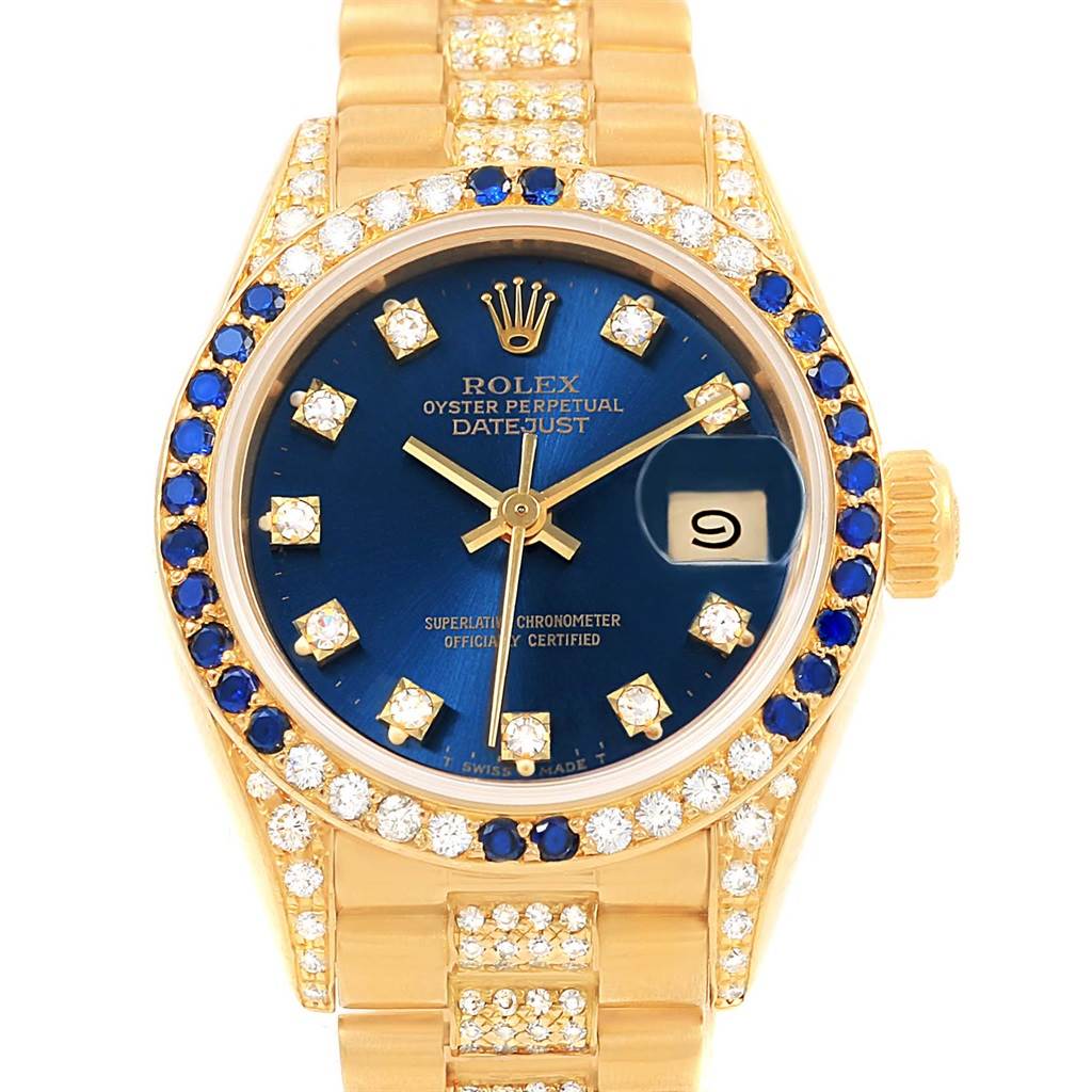 The image shows a frontal view of a Rolex President 69038 Women's Yellow Gold Blue Dial 69038 Women's Yellow Gold Blue Dial Datejust watch, featuring a gold band, blue dial, date window, and diamond accents.