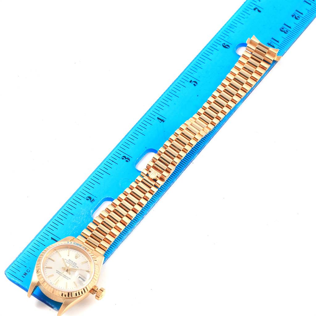 The photo shows the face, case, and the band of the Rolex President 79178 Women's Yellow Gold Silver Dial 79178 Women's Yellow Gold Silver Dial model watch next to a blue ruler.