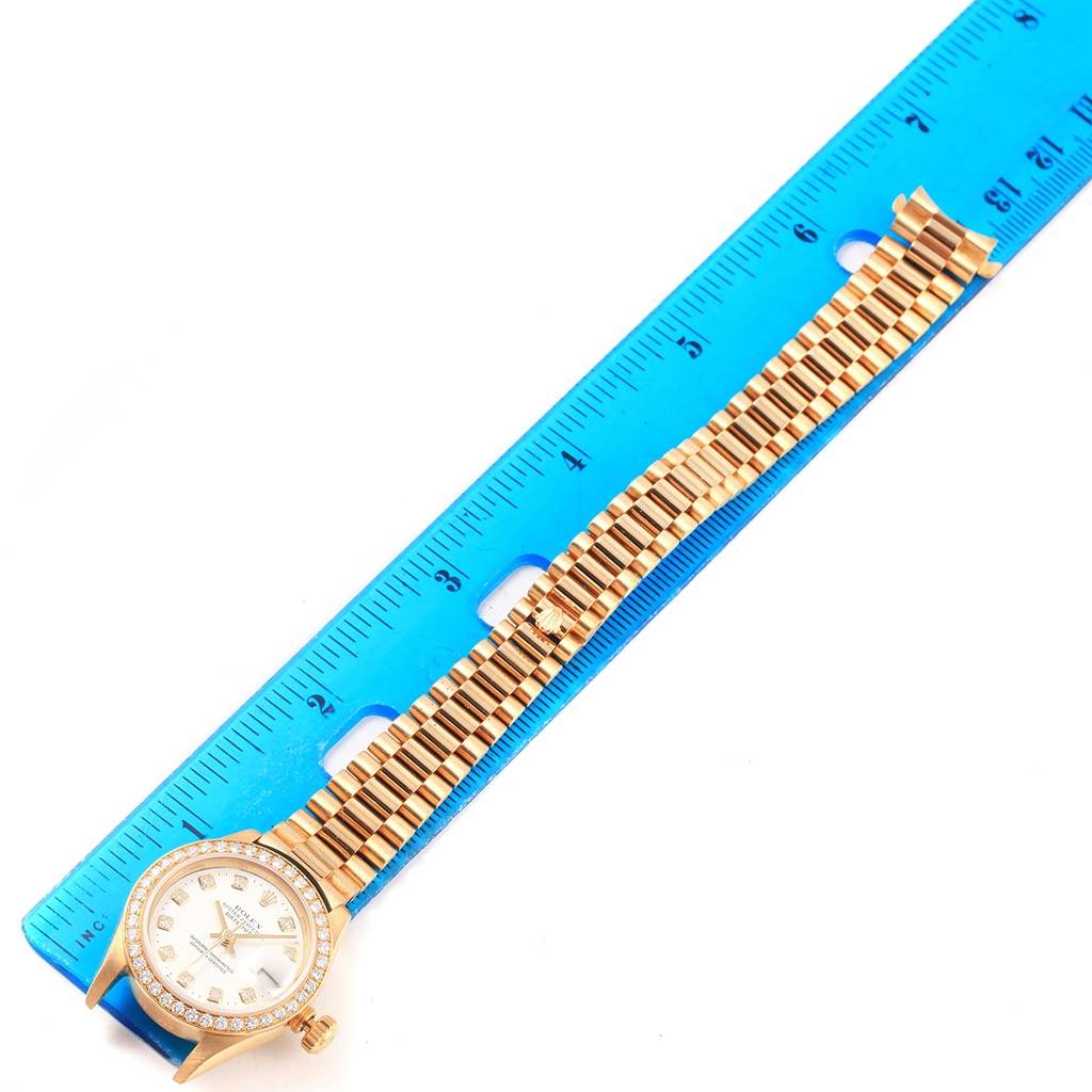 The image shows a Rolex President 79138 Women's Yellow Gold White Dial 79138 Women's Yellow Gold White Dial model watch laid flat next to a ruler to display the length of the band.