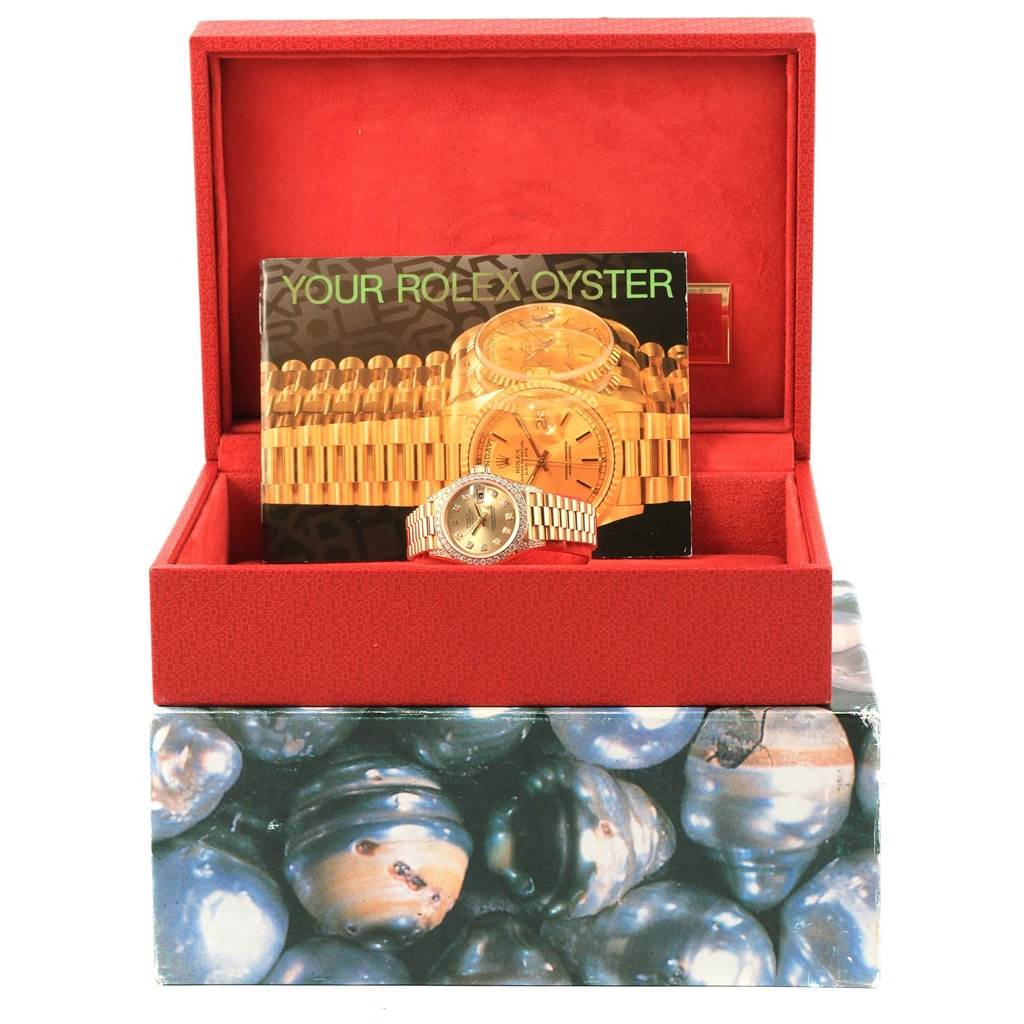 The image shows a Rolex President 69158 Women's Yellow Gold Champagne Dial 69158 Women's Yellow Gold Champagne Dial model watch in a red box with promotional material in the background.