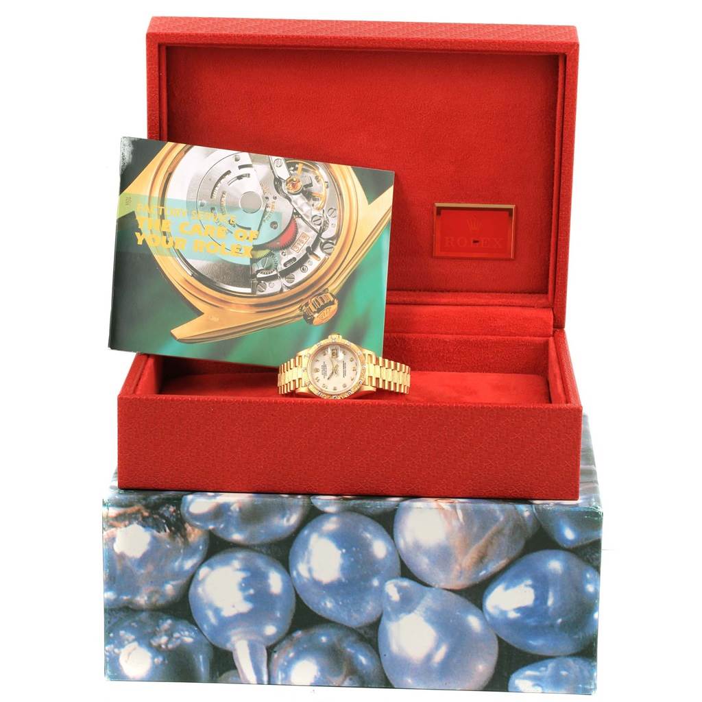 The image shows a Rolex President 69288 Women's Yellow Gold Beige Dial 69288 Women's Yellow Gold Beige Dial model watch inside an open red box with its manual placed behind it.