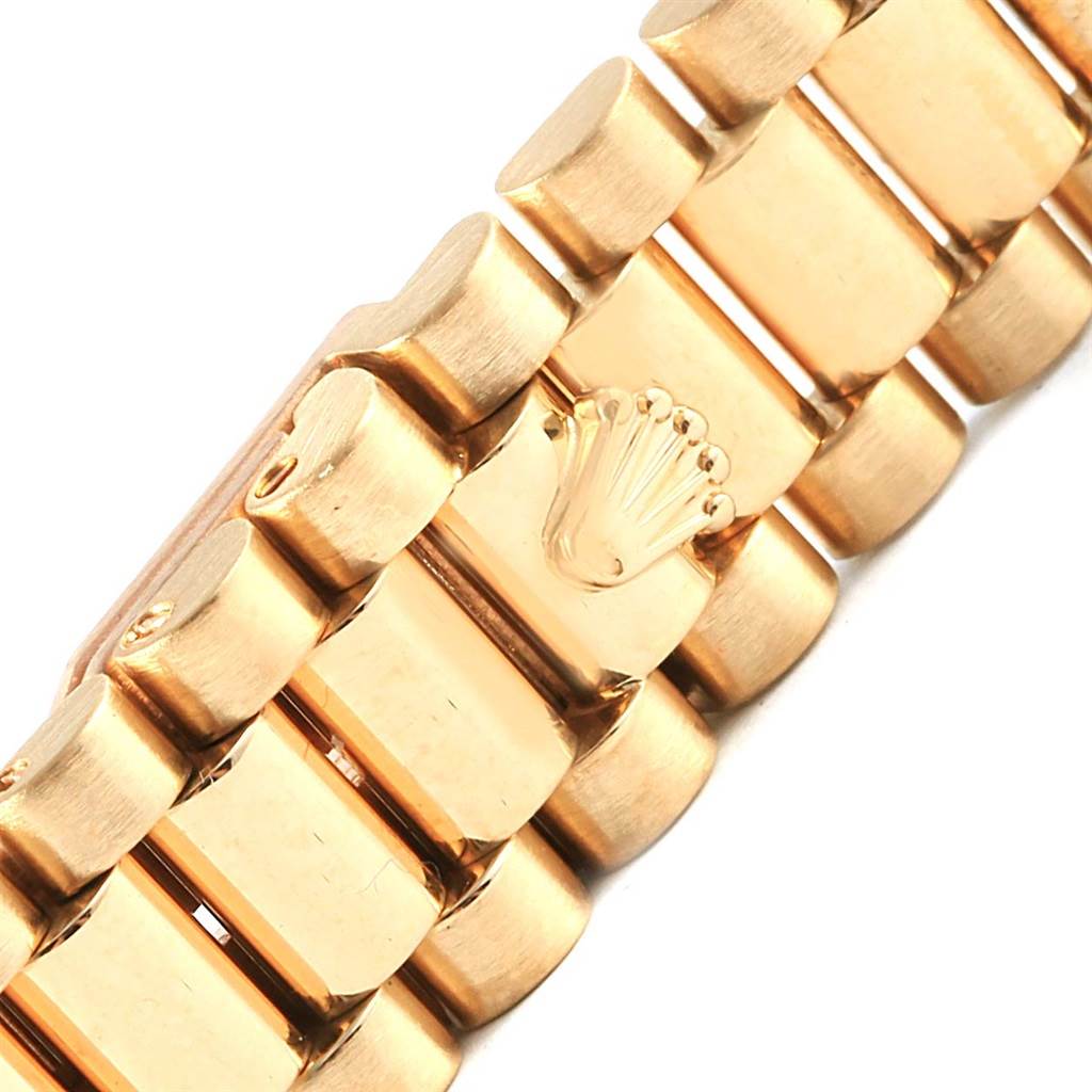 This image shows a close-up of the President bracelet of a Rolex watch, highlighting the iconic crown logo on the clasp.
