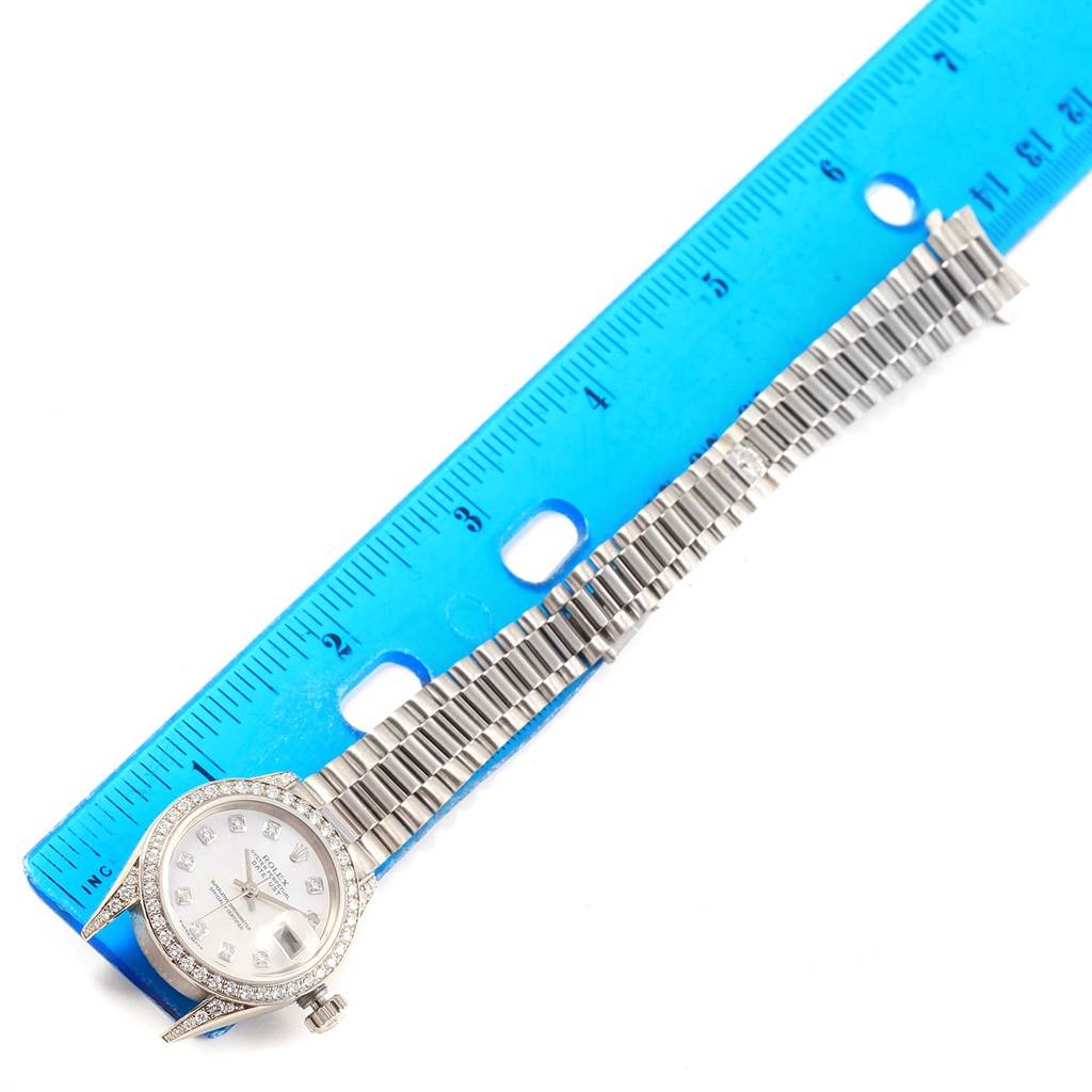 The Rolex President 79159 Women's White Gold Mother of Pearl Dial 79159 Women's White Gold Mother of Pearl Dial watch is shown from an overhead angle, displaying its bezel, dial, and bracelet next to a ruler.