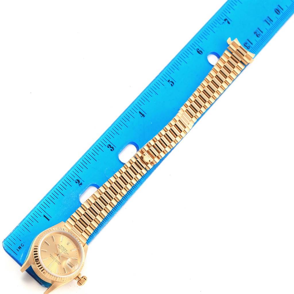 A Rolex President 69178 Women's Yellow Gold Champagne Dial 69178 Women's Yellow Gold Champagne Dial watch is photographed laid flat next to a blue ruler, showing the watch face, strap, and clasp.