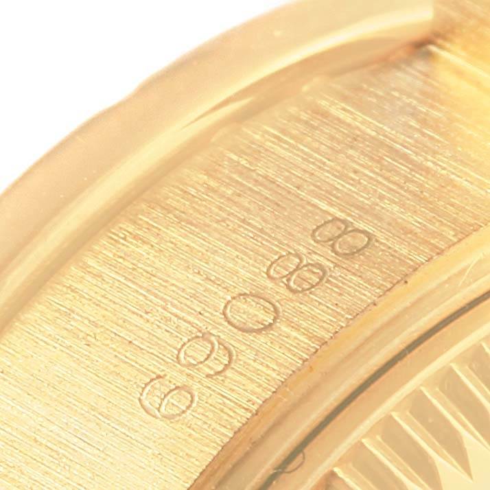 The image shows a close-up of the gold bezel on a Rolex President 69088 Women's Yellow Gold Blue Dial 69088 Women's Yellow Gold Blue Dial model watch, focusing on the engraved markings.