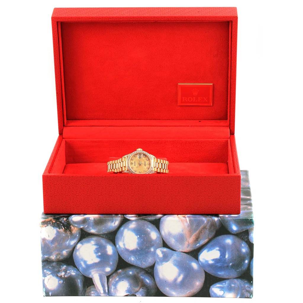 The Rolex President 69198 Women
s Yellow Gold Champagne Dial 69198 Women
s Yellow Gold Champagne Dial model watch is displayed front view in an open red case with the Rolex logo.