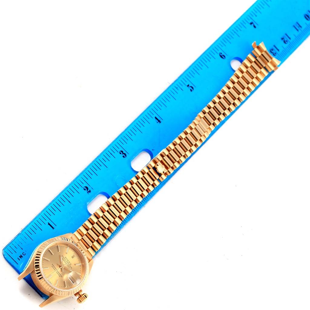 The Rolex President 69178 Women
s Yellow Gold Champagne Dial 69178 Women
s Yellow Gold Champagne Dial model watch is shown laying flat with its bracelet stretched out next to a ruler.