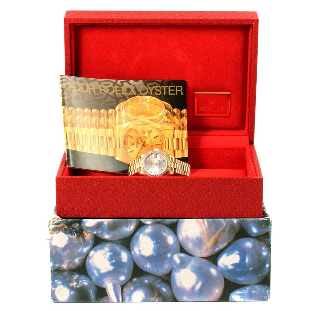 A Rolex President 69138 Women's Yellow Gold Silver Dial 69138 Women's Yellow Gold Silver Dial model watch is displayed in an open, red box with accompanying paperwork.