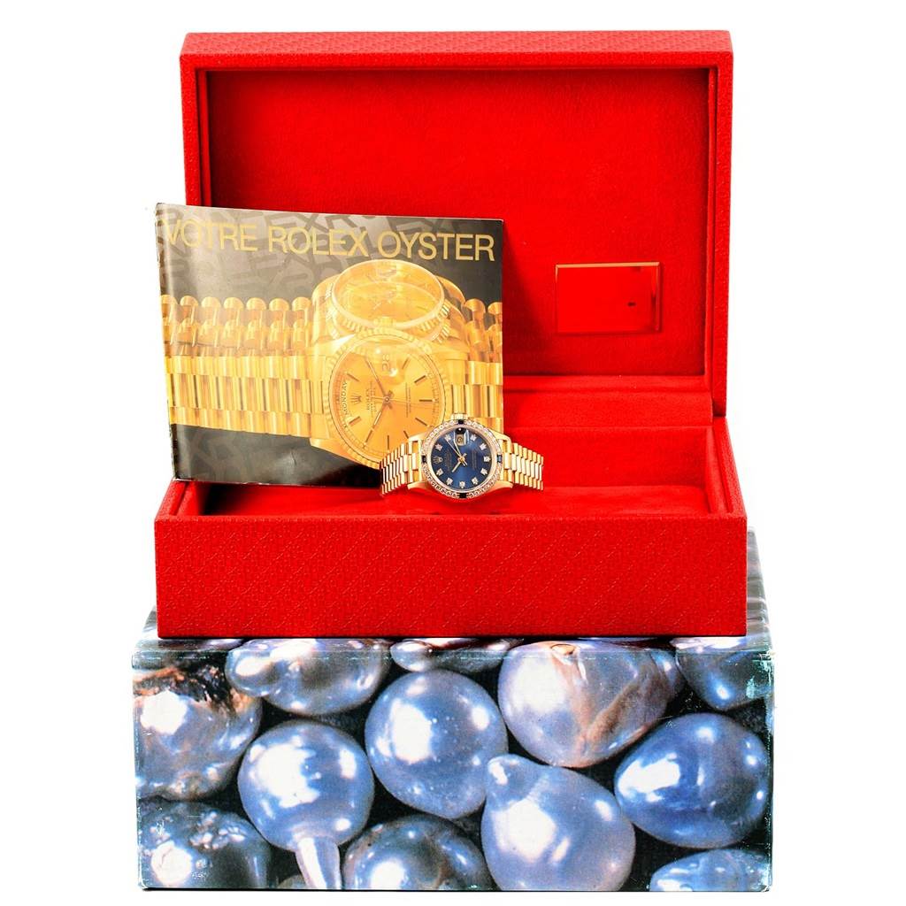 The Rolex President 69178 Women's Yellow Gold Blue Dial 69178 Women's Yellow Gold Blue Dial model watch is shown from a front angle inside its open red box, accompanied by a manual.