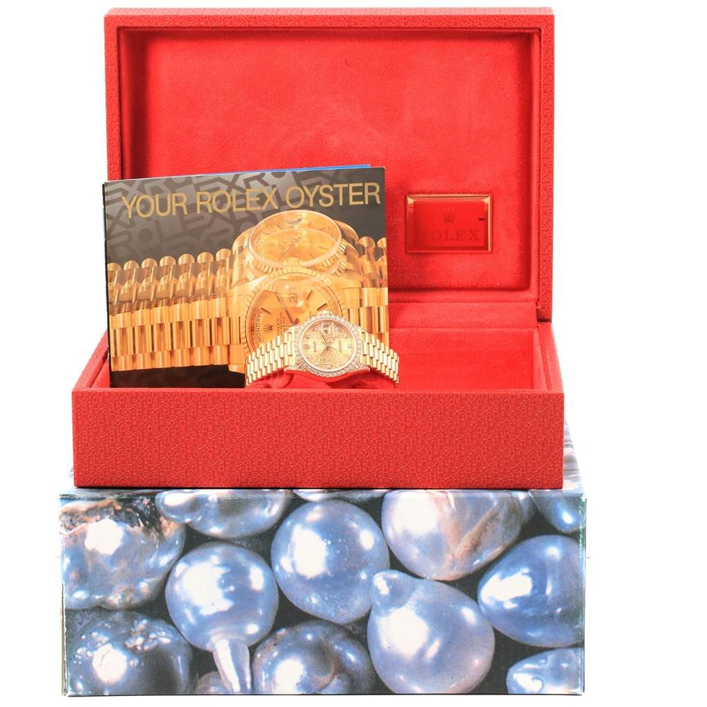 The image shows the Rolex President 69158 Women
s Yellow Gold Champagne Dial 69158 Women
s Yellow Gold Champagne Dial watch inside its open red case with a brochure labeled "Your Rolex Oyster."