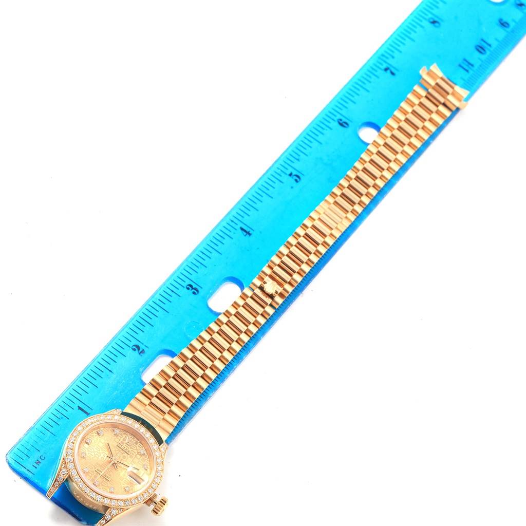 The image shows a Rolex President 69158 Women
s Yellow Gold Champagne Dial 69158 Women
s Yellow Gold Champagne Dial model watch placed next to a ruler, displaying the watch face and full bracelet at a top-down angle.