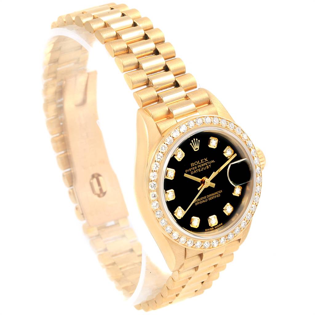 The image shows a Rolex President 69138 Women
s Yellow Gold Black Dial 69138 Women
s Yellow Gold Black Dial model watch at an angle highlighting its gold bracelet, black dial, and diamond bezel.