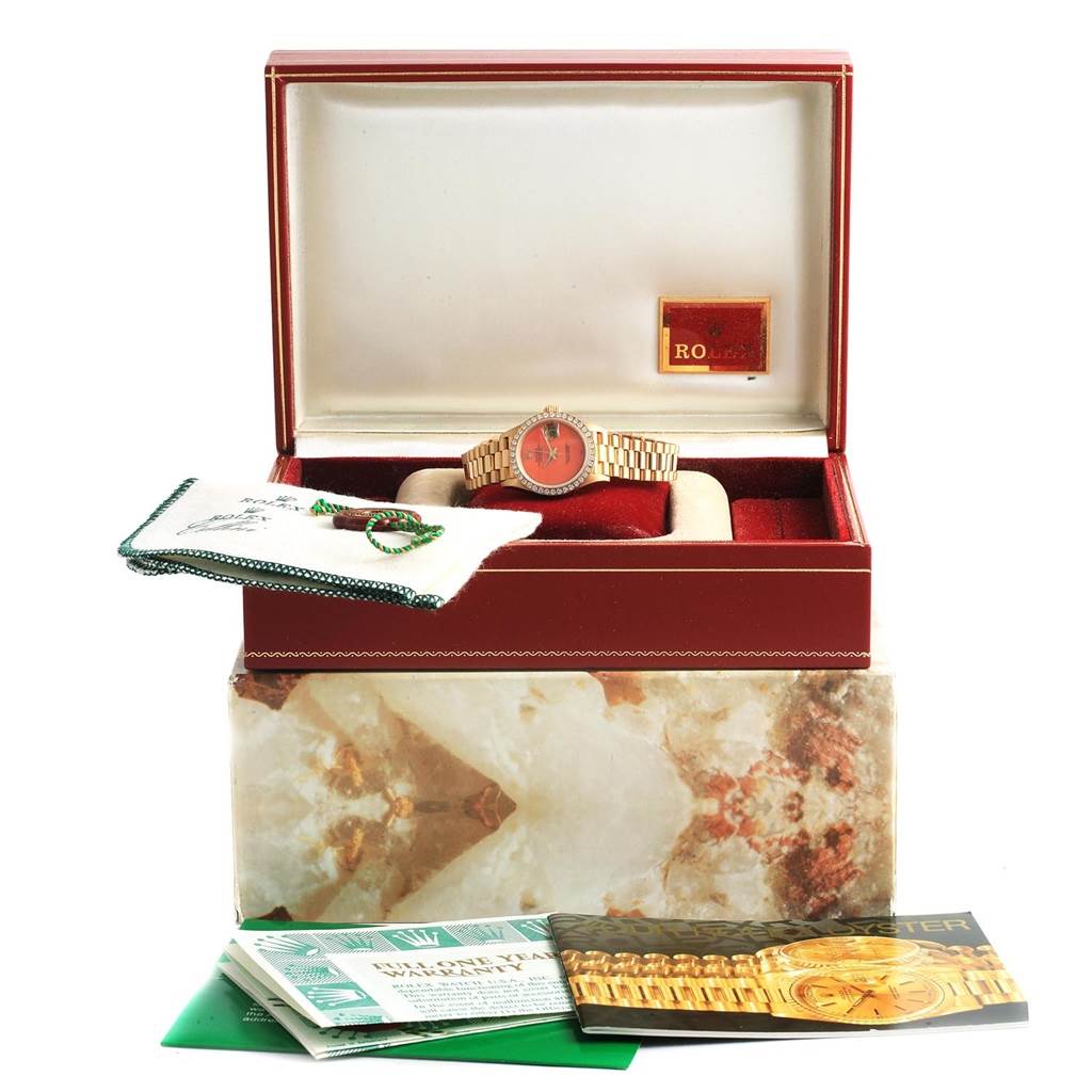 This image shows a Rolex President 69178 Women's Yellow Gold Orange Dial 69178 Women's Yellow Gold Orange Dial model watch in its box along with its accessories and manuals, viewed from the front.