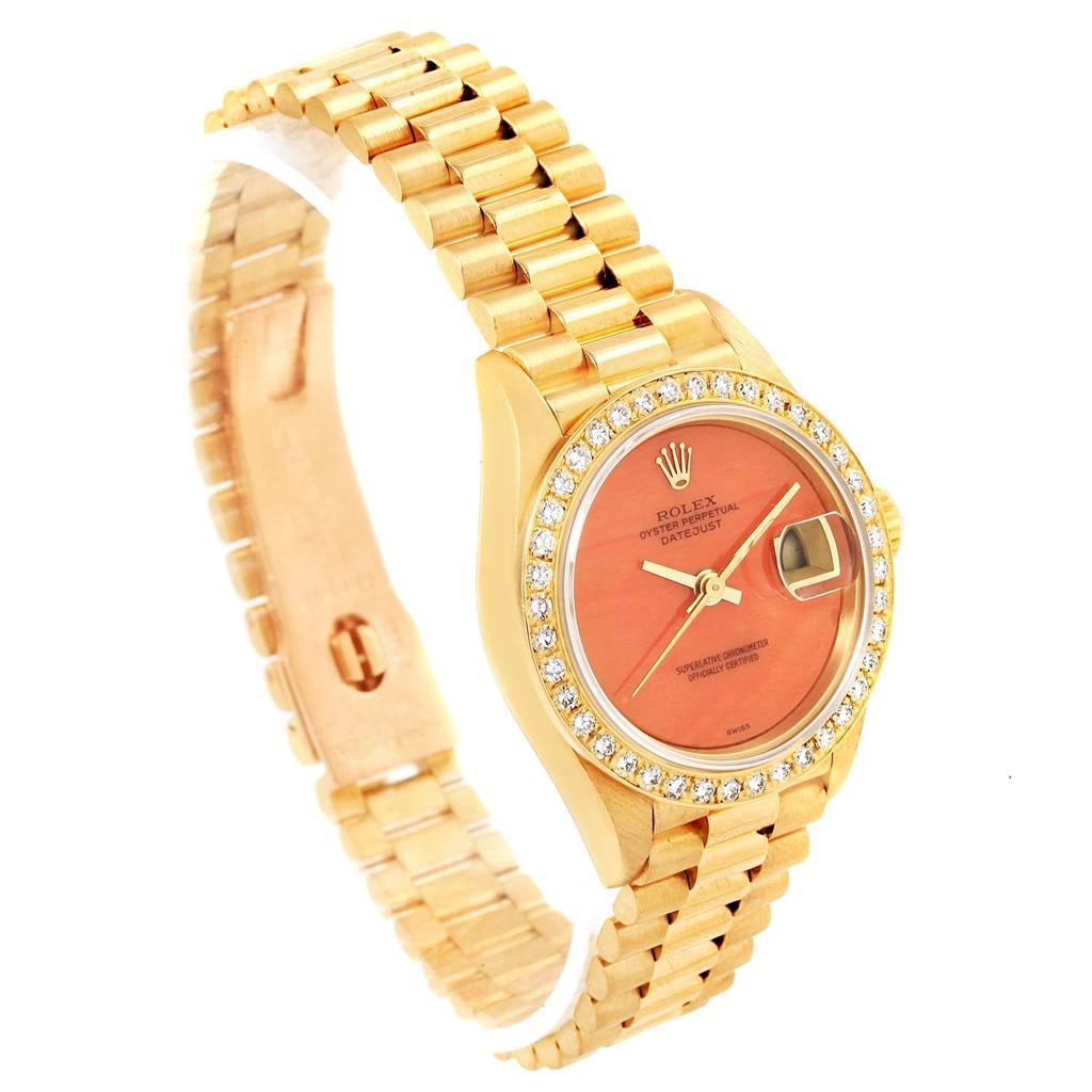 The image shows a side angle view of the Rolex President 69178 Women's Yellow Gold Orange Dial 69178 Women's Yellow Gold Orange Dial model watch, displaying its face, bracelet, and bejeweled bezel.