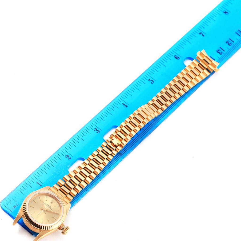 The Rolex President 67198 Women
s Yellow Gold Champagne Dial 67198 Women
s Yellow Gold Champagne Dial model watch is shown lying flat with an emphasis on the dial, bracelet, and part of the clasp next to a ruler.