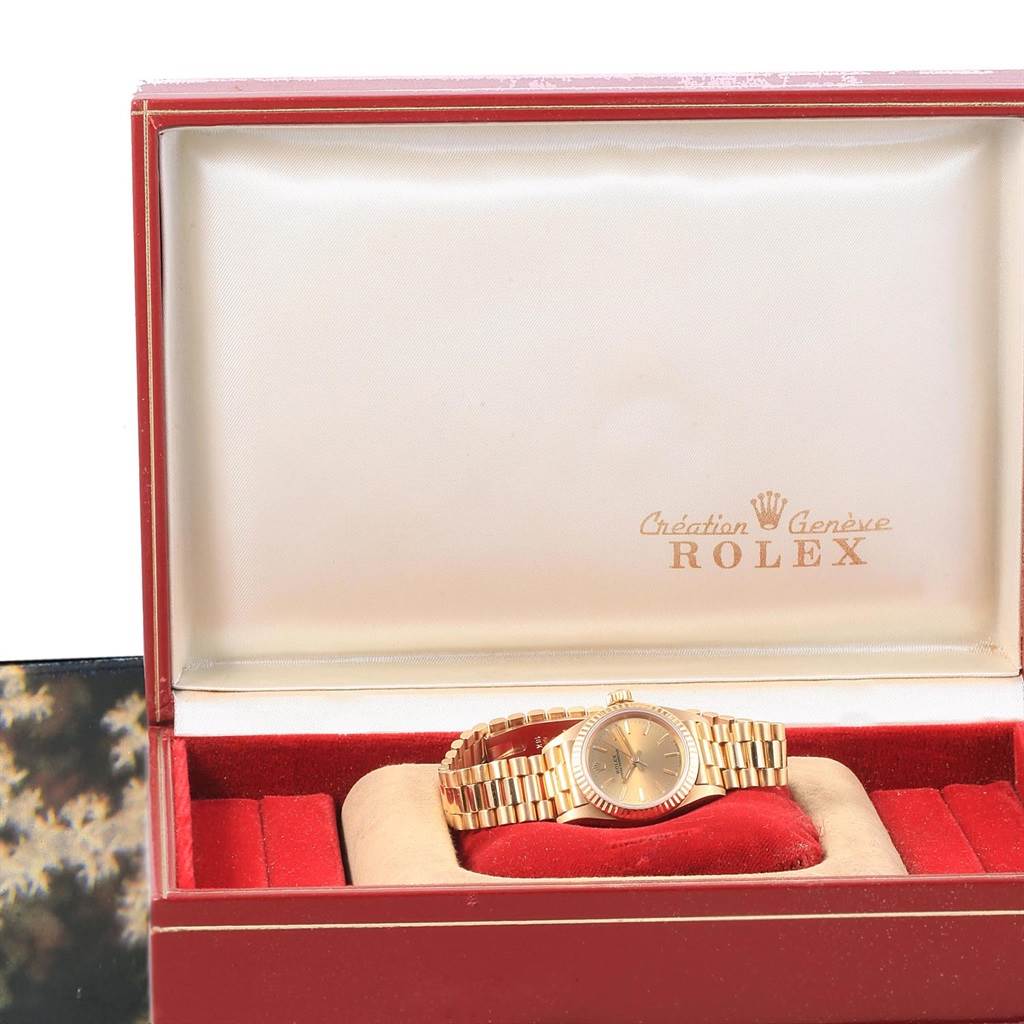 The image shows a Rolex President 67198 Women
s Yellow Gold Champagne Dial 67198 Women
s Yellow Gold Champagne Dial model watch positioned inside an open Rolex box, showcasing the entire watch and bracelet.
