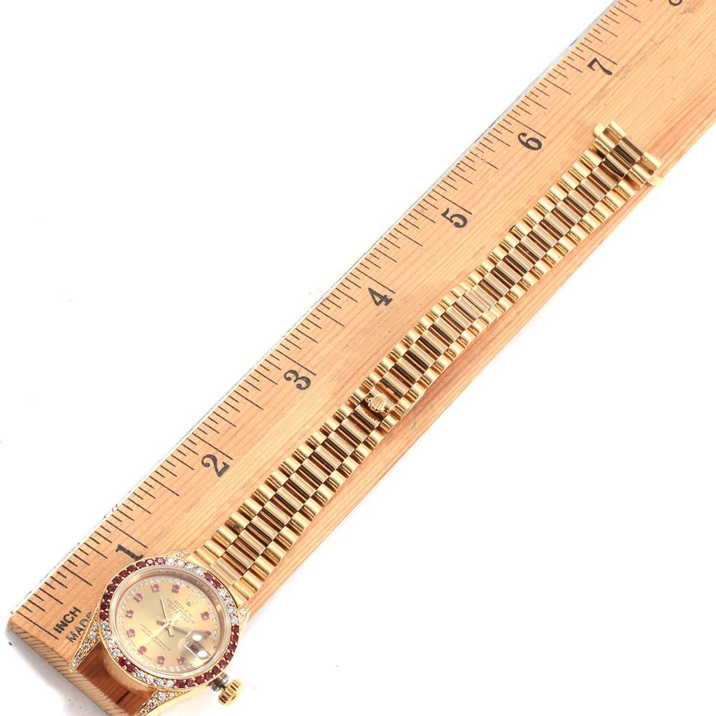 The image shows a Rolex President 69038 Women
s Yellow Gold Champagne Dial 69038 Women
s Yellow Gold Champagne Dial model watch, laid flat alongside a ruler, highlighting the face and full bracelet on top view.