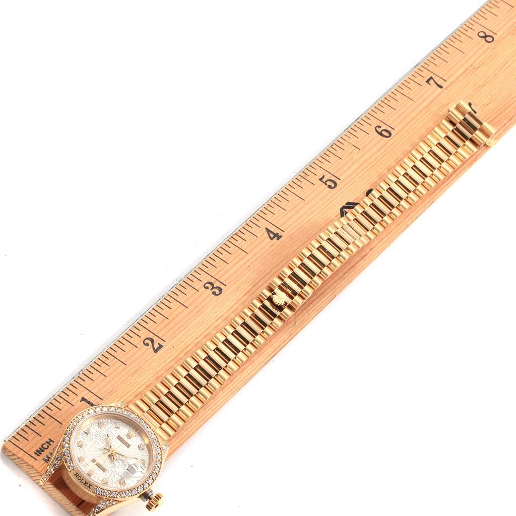 The image shows the Rolex President 69158 Women
s Yellow Gold Silver Dial 69158 Women
s Yellow Gold Silver Dial model watch positioned alongside a ruler, highlighting the face and metal bracelet band.