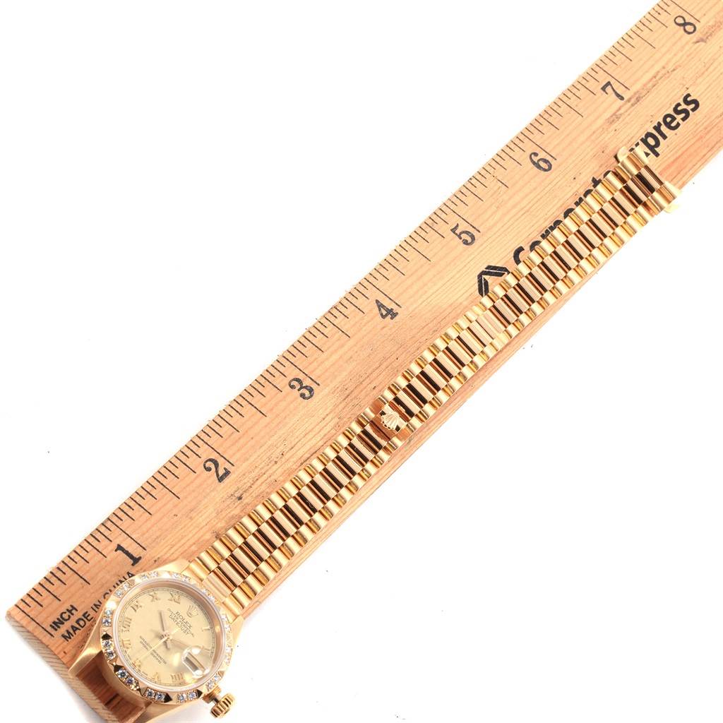 The Rolex President 69258 Women's Yellow Gold Champagne Dial 69258 Women's Yellow Gold Champagne Dial model watch is shown from a top-down angle, displaying the face and full length of the band alongside a ruler.