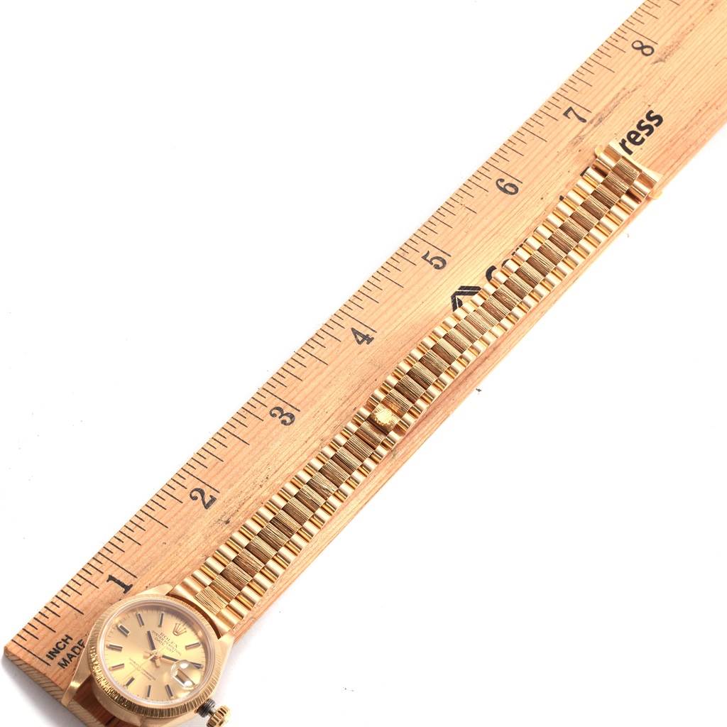 The image shows a Rolex President 69278 Women
s Yellow Gold Champagne Dial 69278 Women
s Yellow Gold Champagne Dial model watch placed alongside a ruler, highlighting its face and bracelet.