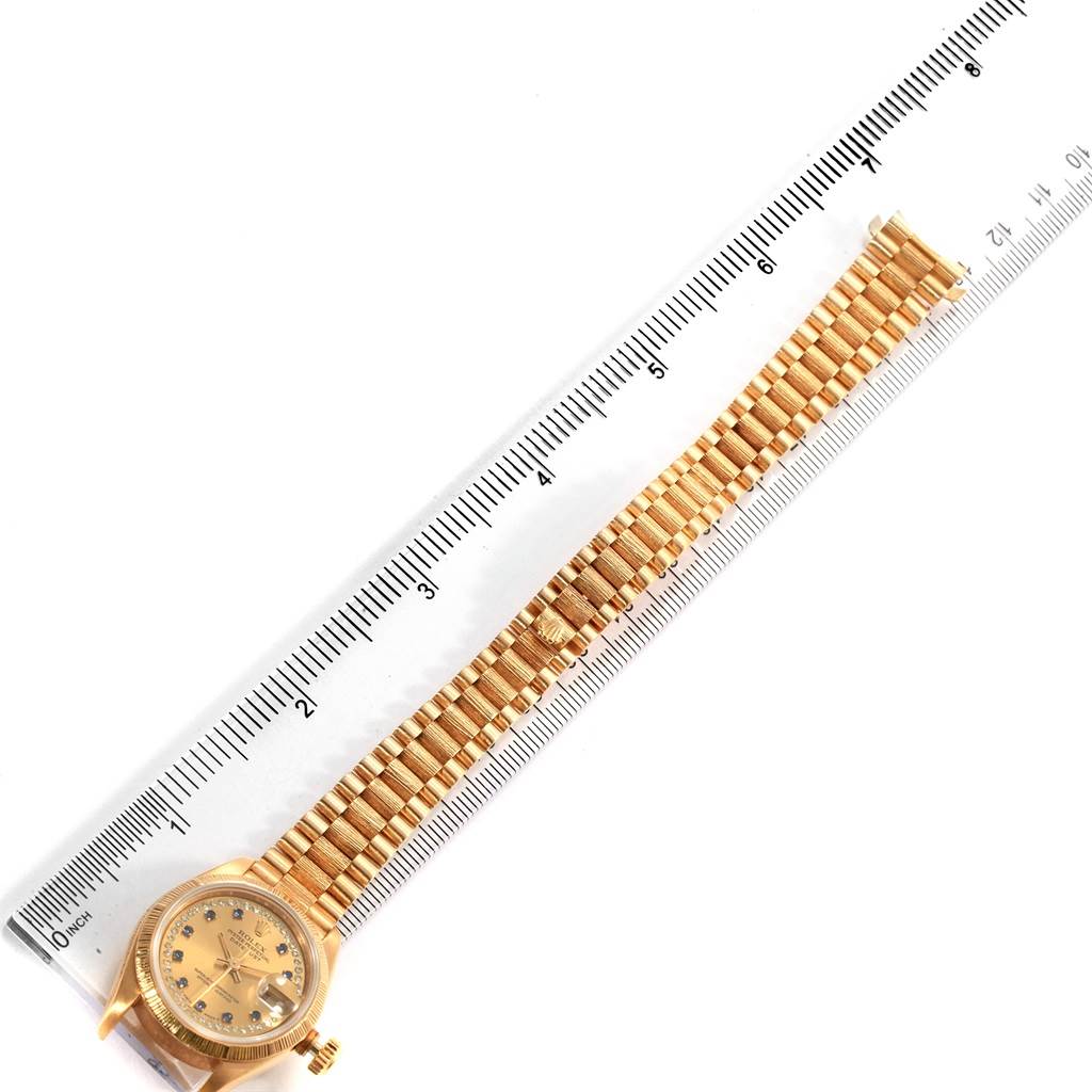 The image shows a Rolex President 69038 Women's Yellow Gold Champagne Dial 69038 Women's Yellow Gold Champagne Dial model watch laid flat with its gold bracelet and face visible, placed alongside a measuring ruler.