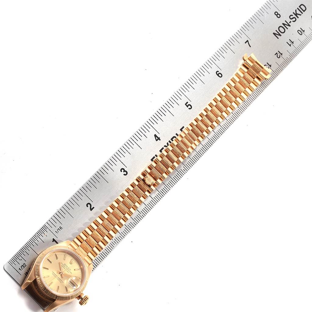 The Rolex President 69278 Women
s Yellow Gold Champagne Dial 69278 Women
s Yellow Gold Champagne Dial model watch is shown from a top angle, displaying its dial, crown, and bracelet alongside a ruler.