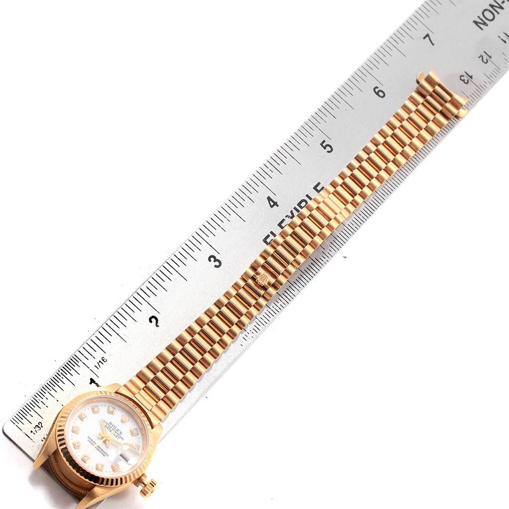 The image shows a Rolex President 69178 Women's Yellow Gold White Dial 69178 Women's Yellow Gold White Dial model watch laid next to a ruler, displaying its bracelet and partially its dial from a top-down angle.