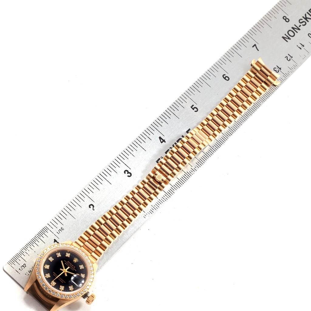This image shows the full view of a Rolex President 69138 Women
s Yellow Gold Black Dial 69138 Women
s Yellow Gold Black Dial model watch, including its face and bracelet, aligned next to a measurement ruler.