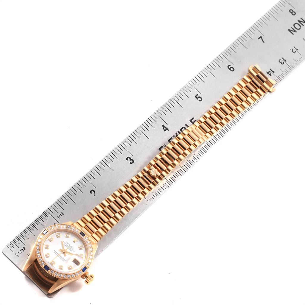 The image shows a Rolex President 79088 Women
s Yellow Gold Mother of Pearl Dial 79088 Women
s Yellow Gold Mother of Pearl Dial watch laying flat with a ruler measuring its length, displaying the face and bracelet fully.